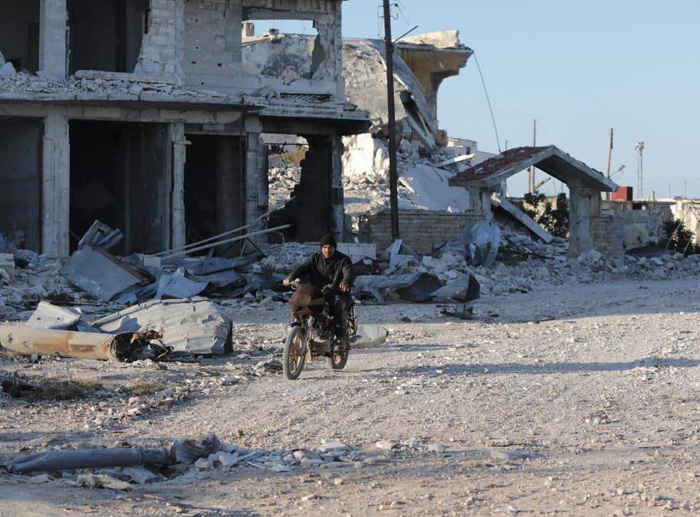 A Syrian man rides his motorcycle in a town ravaged by attacks from pro-Assad forces in Idlib province