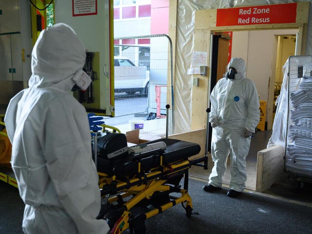 An emergency car assistant and a paramedic wait to safely remove their PPE3-level clothing in the ambulance bay of a hospital in Southampton amid the coronavirus pandemic