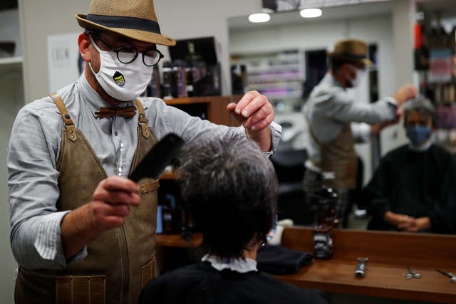 French hairdresser Marc Mauny tends to his first customer during the midnight reopening of his salo  in Mayenne