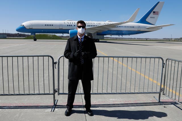 A US Secret Service agent wears a mask while Mike Pence's Air Force Two prepares for takeoff.