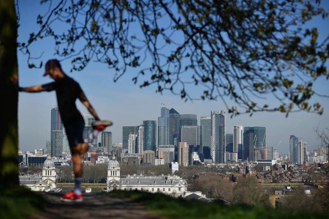 London's financial district Canary Wharf is seen as a man exercises in Greenwich Park in South London on 23 March 2020