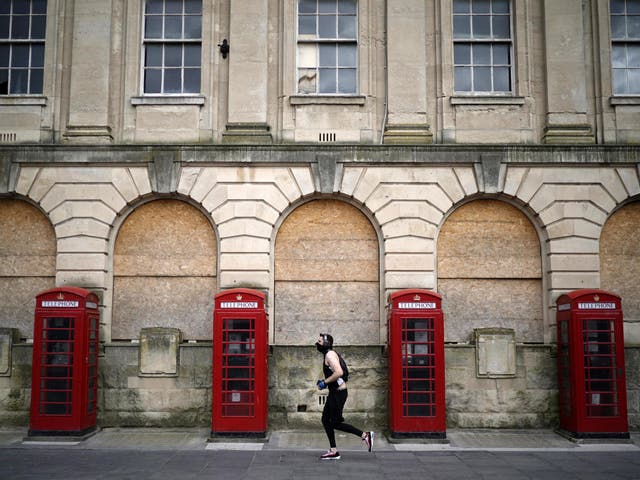 A man wearing a mask jogs past red phone boxes in Blackpool town centre