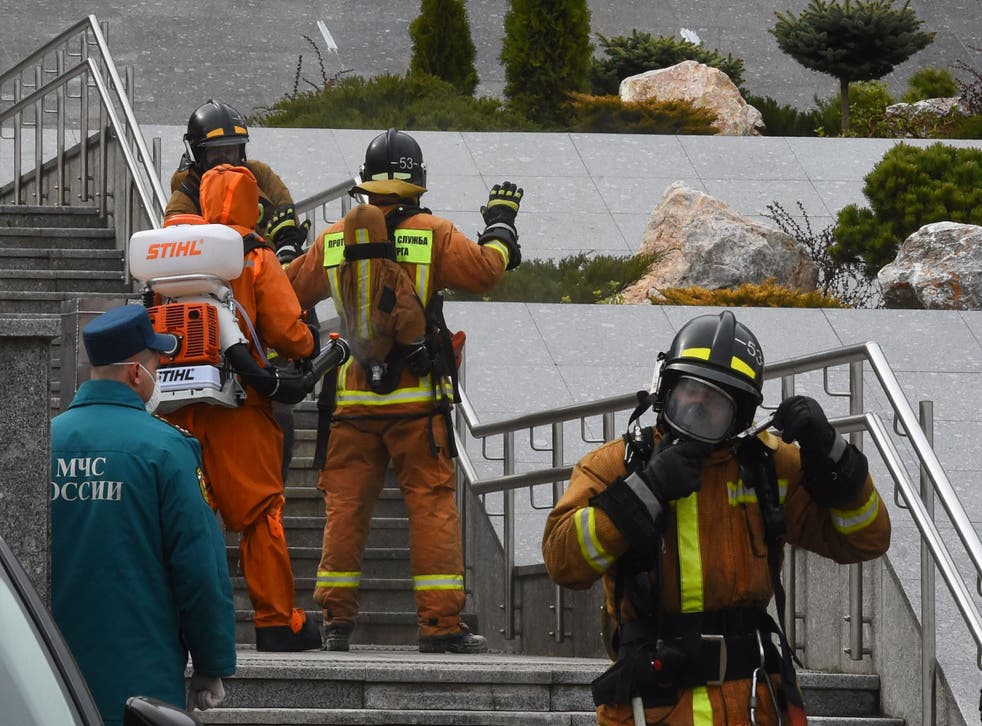 Emergencies personnel wearing protective gear spray disinfectant on colleagues at the site of a fire at the Saint George hospital in Saint Petersburg
