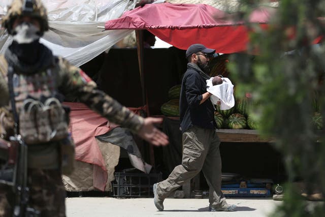 An Afghan security officer carries a baby after gunmen attacked a maternity hospital in Kabul on 12 May, 2020