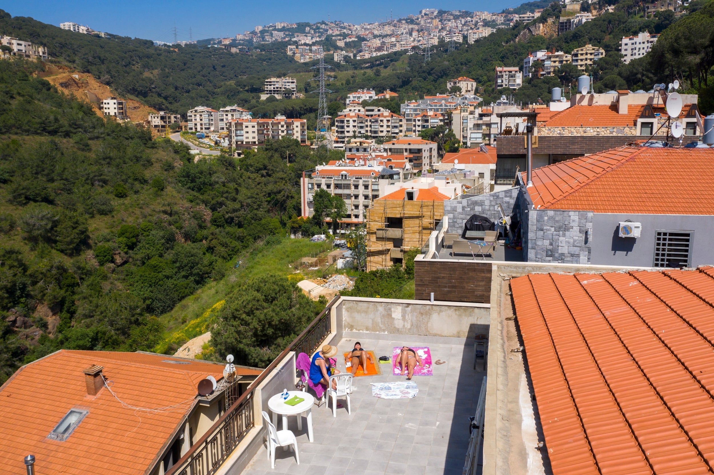 Lebanese women sunbathe on the rooftop of their home in Mansourieh village near Beirut