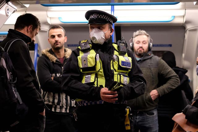 A police officer with commuters as they travel in the morning rush hour on the Victoria Line on 13 May