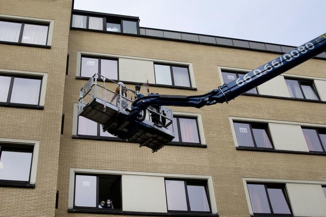 Bernadette Focant, waits at her third floor window as she receives a visit by crane platform from her sister Terry at the La Cambre care home in Belgium