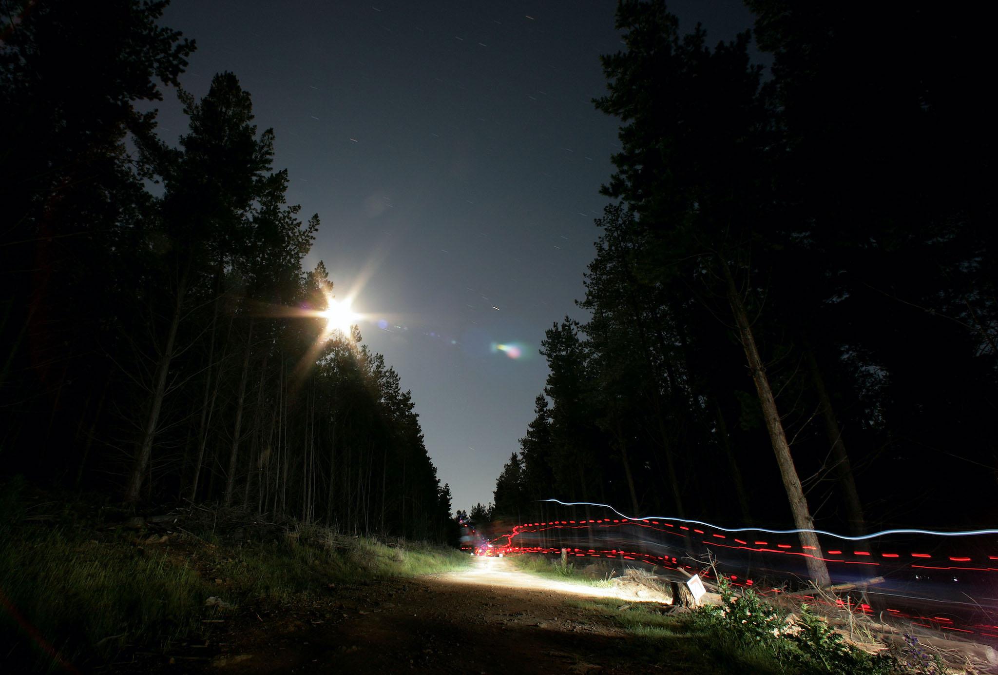 Riders leave light trails on a full-moon lit night during the Mont 24 Hour MTB Race held at Majura Pines forest