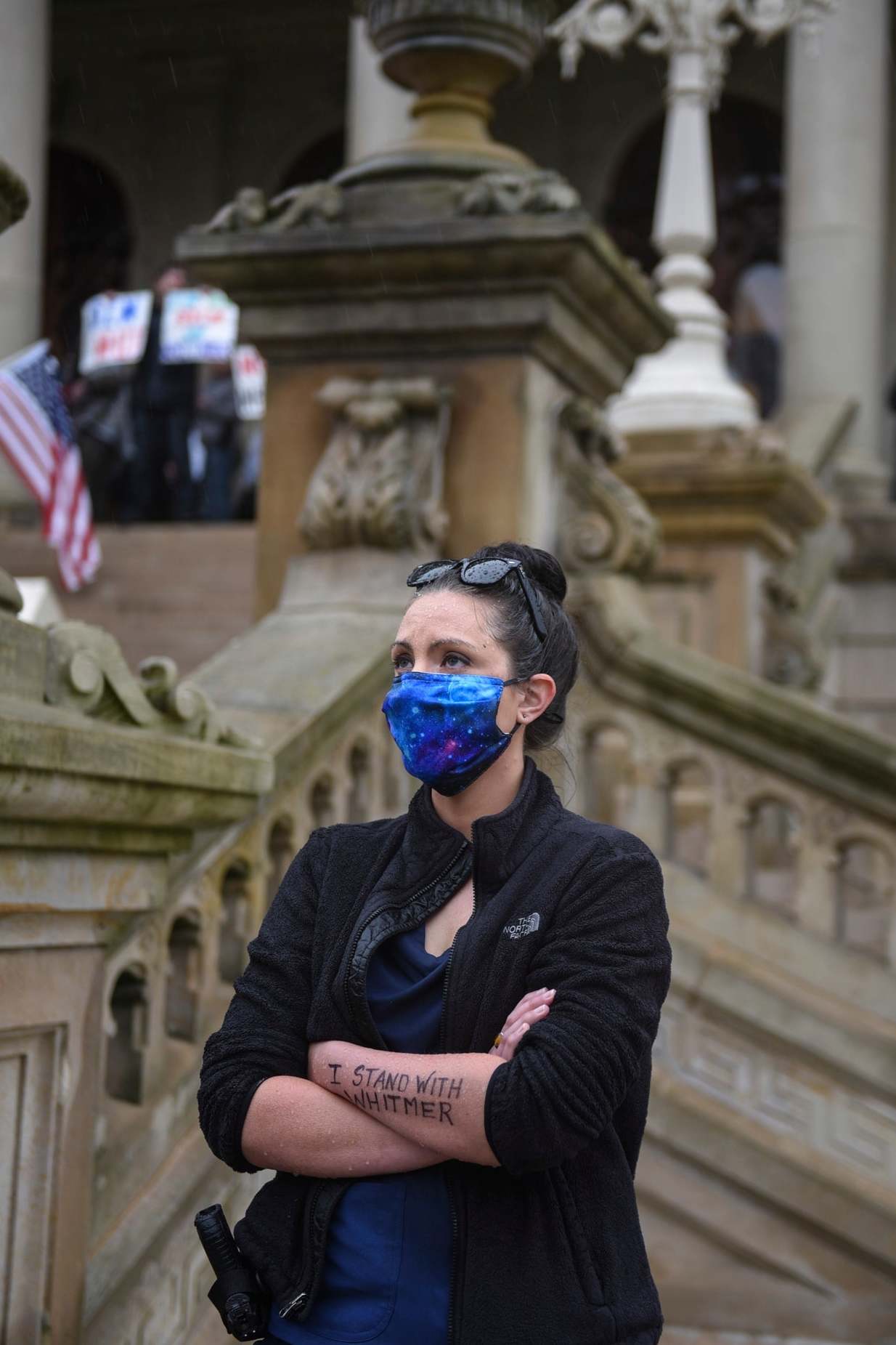 An armed nurse with the message 'I stand with Whitmer' written on her arm takes part in a counter-protest in favour of lockdown measures during a demonstration against them at the state capitol in Lansing, Michigan