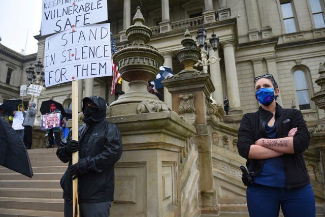 An armed medic with the message 'I stand with Whitmer' written on her arm takes part in a counter-protest in favour of lockdown measures during a demonstration against them at the state capitol in Lansing, Michigan