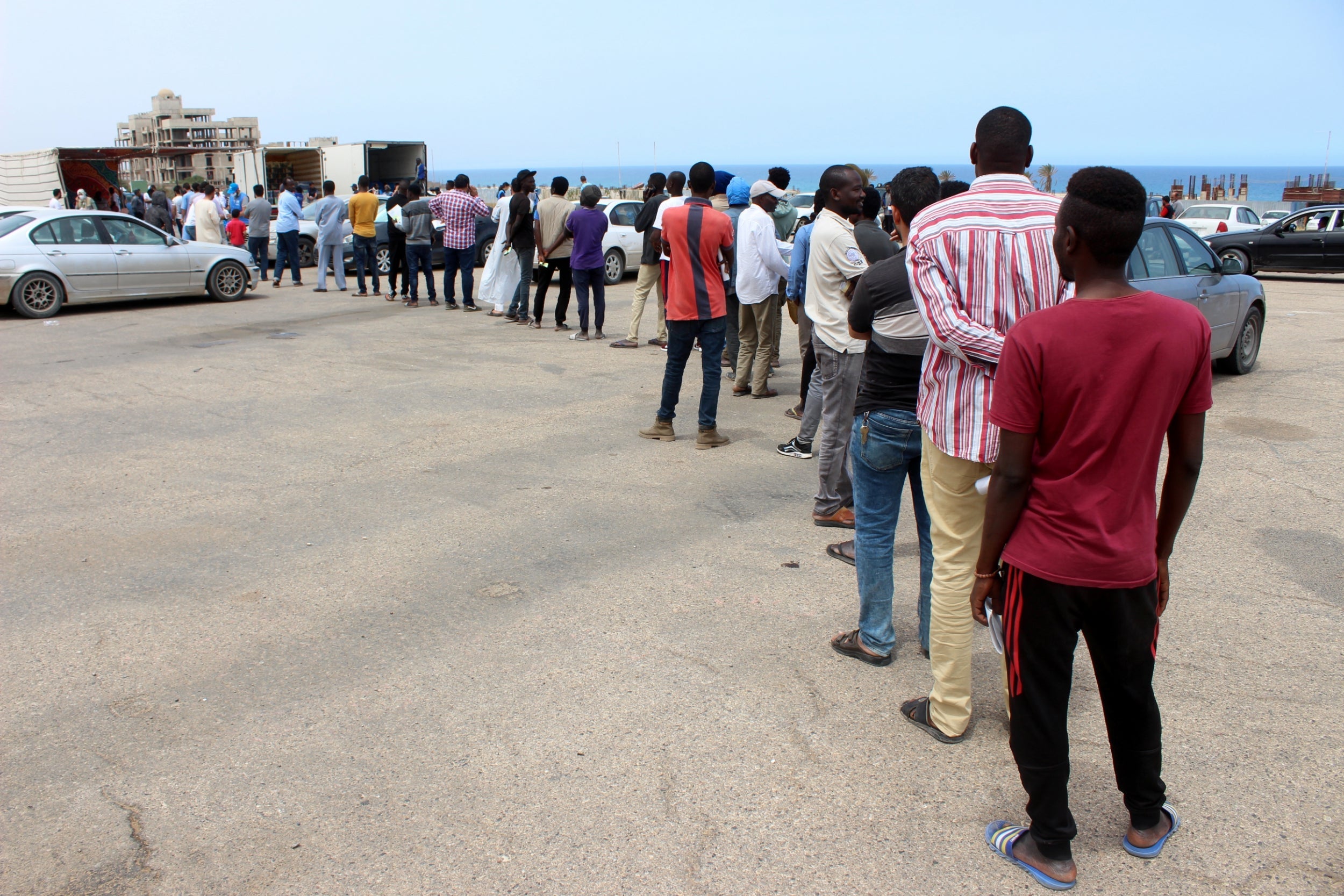 Migrants queue to receive food packages distributed by UNHCR during the holy month of Ramadan in Tripol