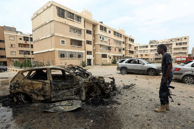 A fighter loyal to Libya's UN-recognised Government of National Accord (GNA) stands next to a destroyed car following bombardment earlier in the day in the residential Bab Bin Ghashir neighbourhood in Tripoli