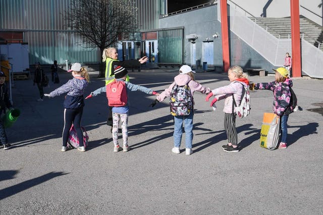 A teacher guides children how to keep the social distancing rules as pupils arrive to start the primary school in Helsinki, Finland, 14 May 2020