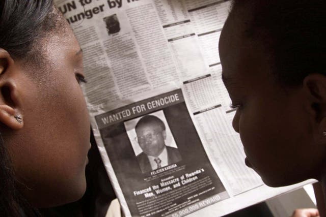 Readers look at a newspaper on 12 June 2002 in Nairobi, Kenya, carrying the photograph of Felicien Kabuga