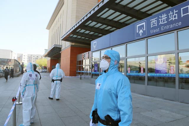 Police officers in protective suits are seen in front a closed entrance to a train station in Jilin City on Wednesday