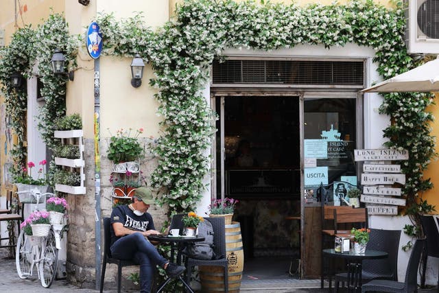 A man sits outside a bar in the Trastevere district of Rome
