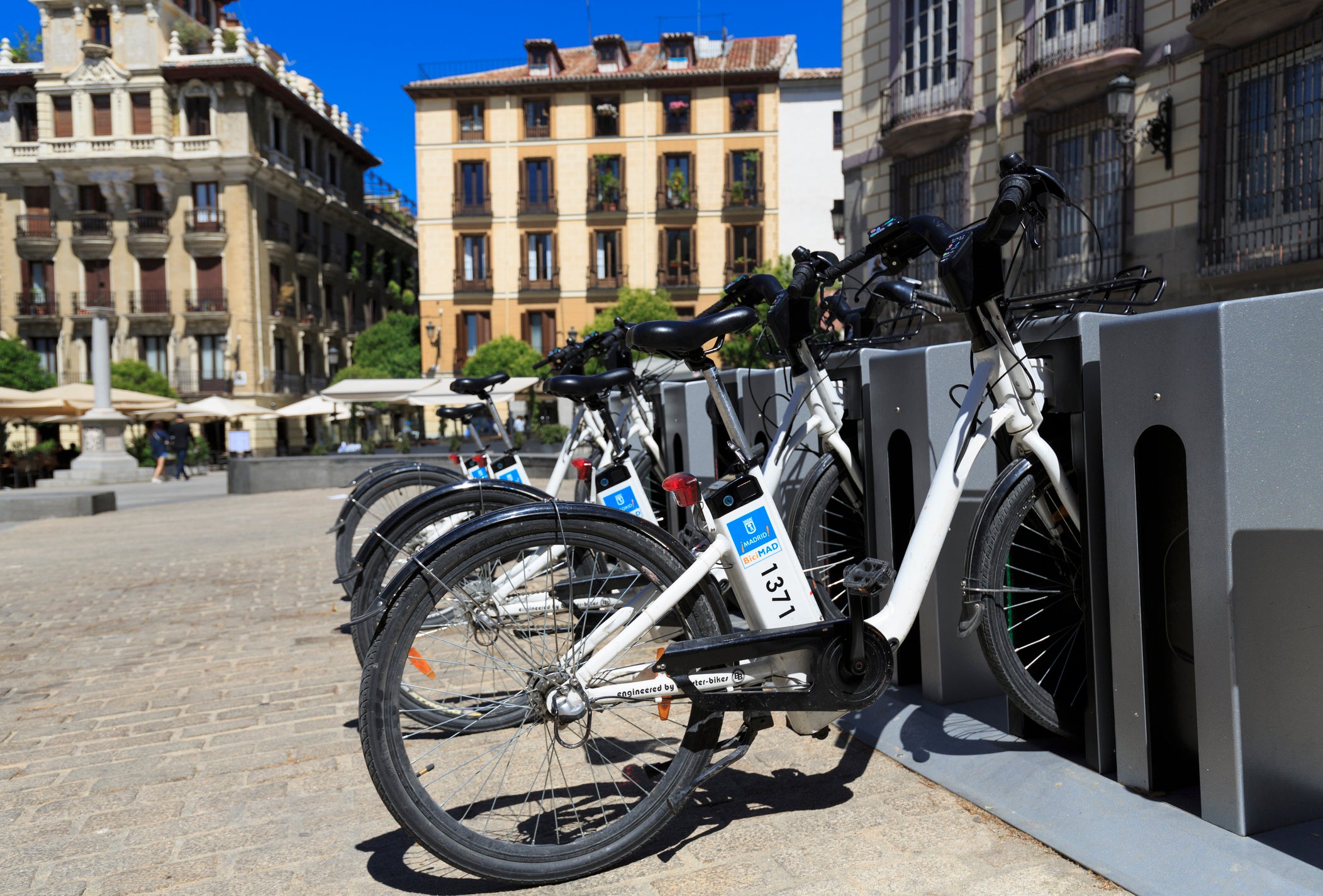 Electric BiciMAD bikes charging up in a plaza in Madrid. These bikes are electrically power assisted and are available for hire by members of the public. Introduced in 2015, they have proved popular with tourists and locals