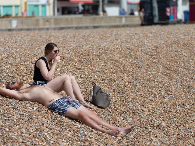 A couple sunbathe on Brighton Beach on May 09, 2020 in Brighton, England