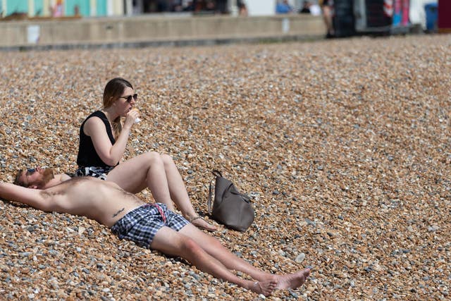 A couple sunbathe on Brighton Beach on May 09, 2020 in Brighton, England