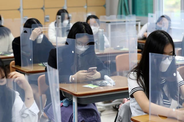 Senior students wait for class to begin with plastic boards placed on their desks at Jeonmin High School in Daejeon, South Korea, Wednesday