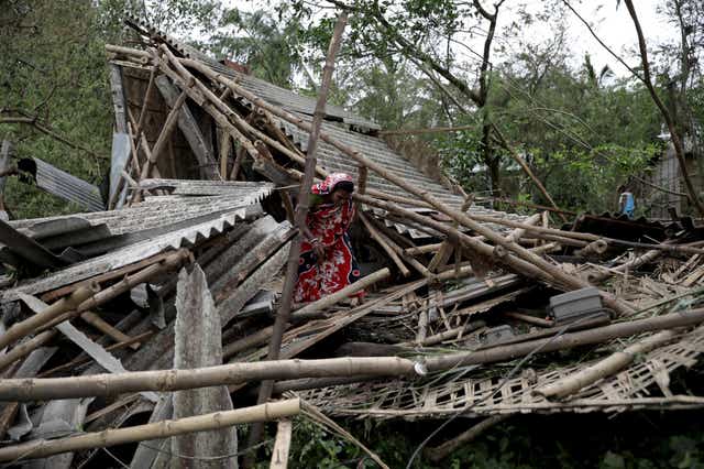 Family members stand among the debris of their destroyed home in Bokkhali village near the Bay of Bengal, India, on Thursday