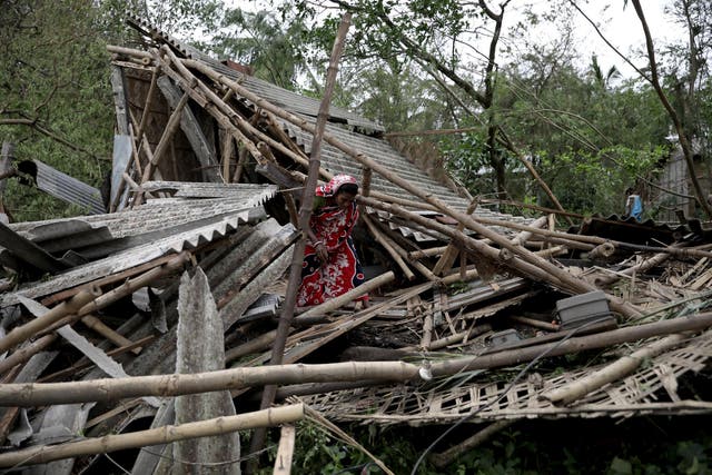 Family members stand among the debris of their destroyed home in Bokkhali village near the Bay of Bengal, India, on Thursday