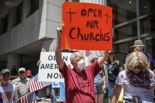 Demonstrators hold up signs demanding their church in California be reopened earlier this month