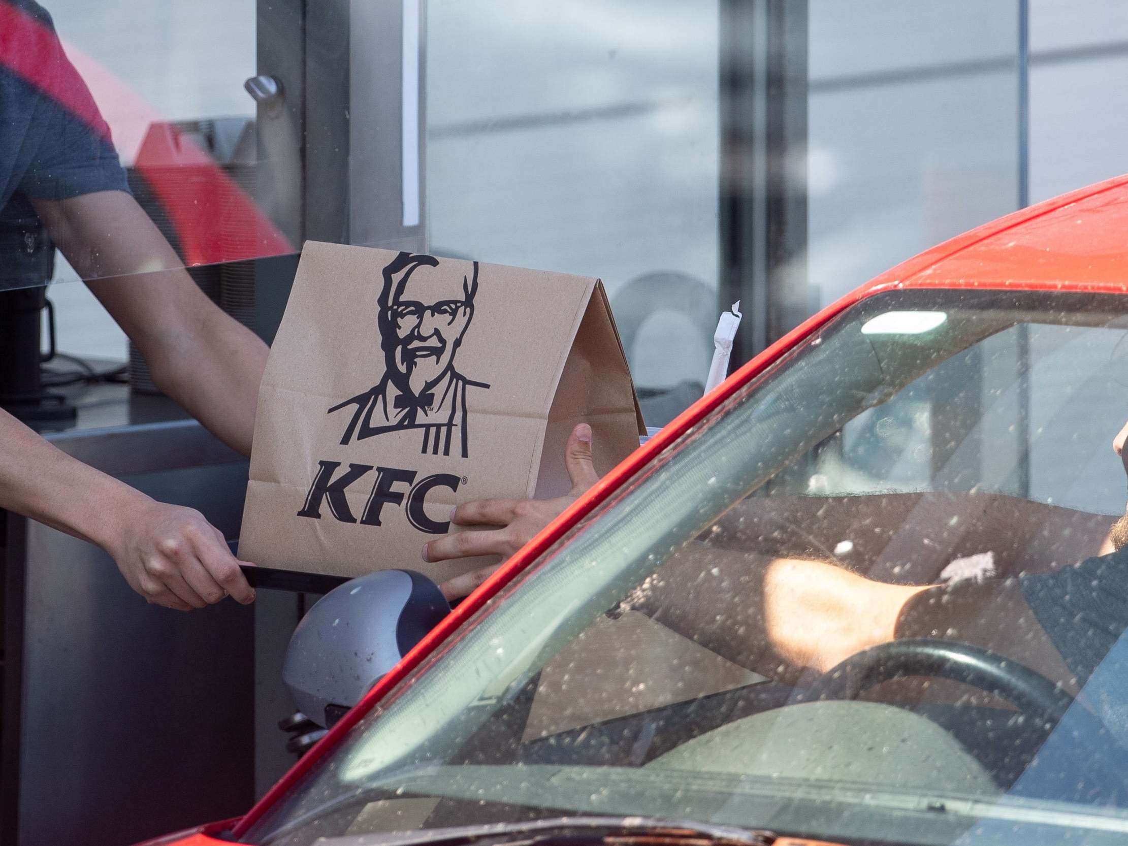 A member of staff hands an order to a customer at a KFC drive-through in Leicester