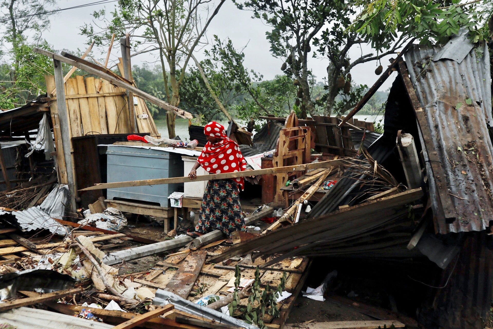 A woman in Satkhira, Bangladesh, clears the remains of her house that was demolished by Cyclone Amphan.