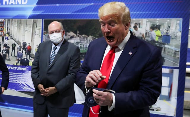 Donald Trump holds a face mask with a presidential seal on it that he said he had been wearing earlier on a visit to a Ford plant in Ypsilanti, Michigan