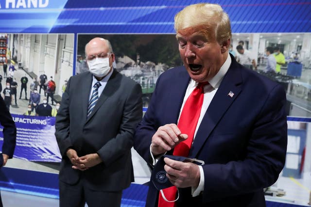 Donald Trump holds a face mask with a presidential seal on it that he said he had been wearing earlier on a visit to a Ford plant in Ypsilanti, Michigan