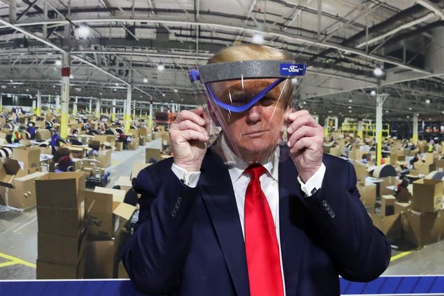Donald Trump holds up a protective face shield during a visit to the Ford Rawsonville Components Plant in Ypsilanti, Michigan