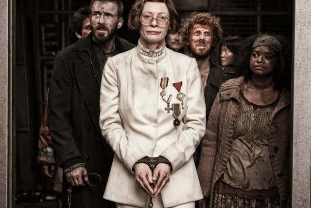 Tilda Swinton stars as Minister Mason – a ghastly caricature of the human form, with her piggy nose, prominent teeth, itchy wig, and fake war medals