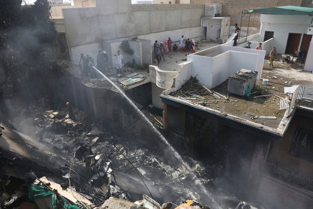 Fire brigade staff try to put out fire caused by plane crash in Karachi, Pakistan