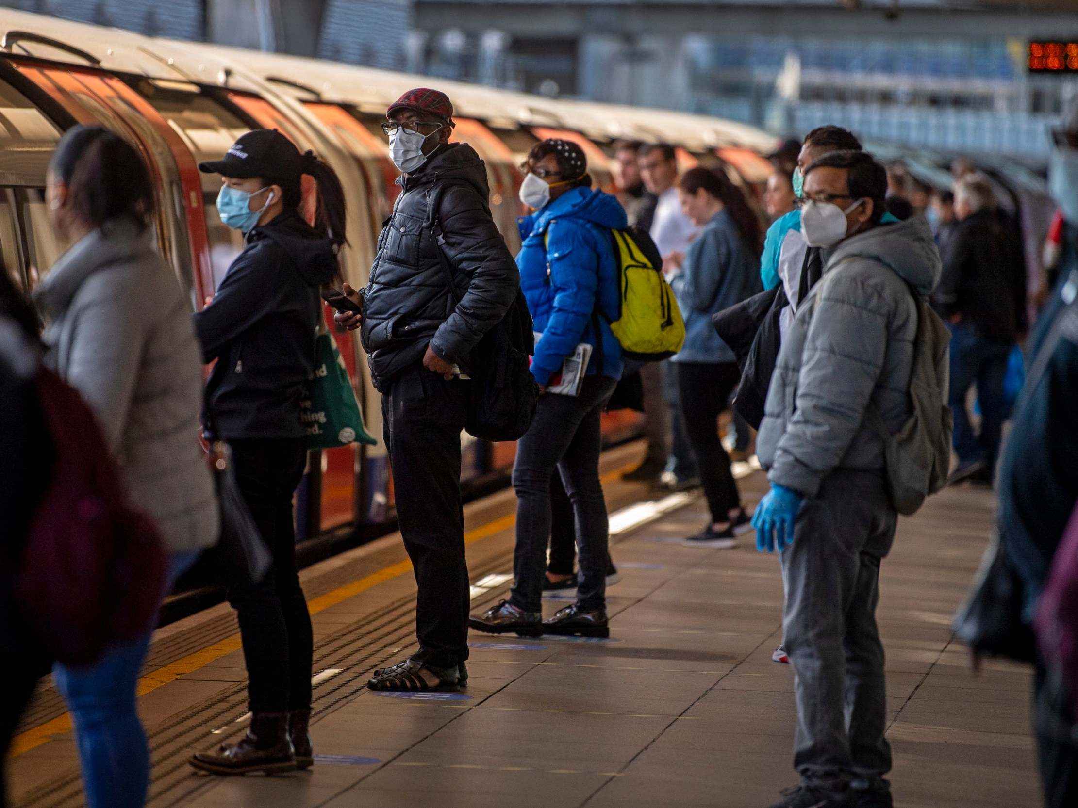 Passengers wearing face masks on a platform at Canning Town underground station in London