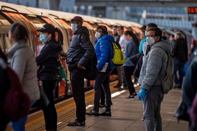 Passengers wearing face masks on a platform at Canning Town underground station in London