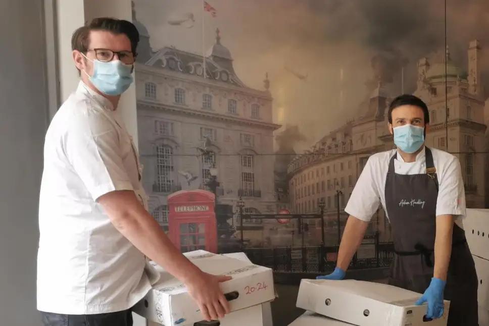 Adam Handling, left, and Steven Kerr with meals created at Frog by Adam Handling in Covent Garden for key workers, shelters, food banks and the YMCA