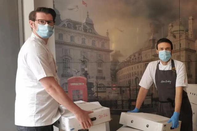 Adam Handling, left, and Steven Kerr with meals created at Frog by Adam Handling in Covent Garden for key workers, shelters, food banks and the YMCA