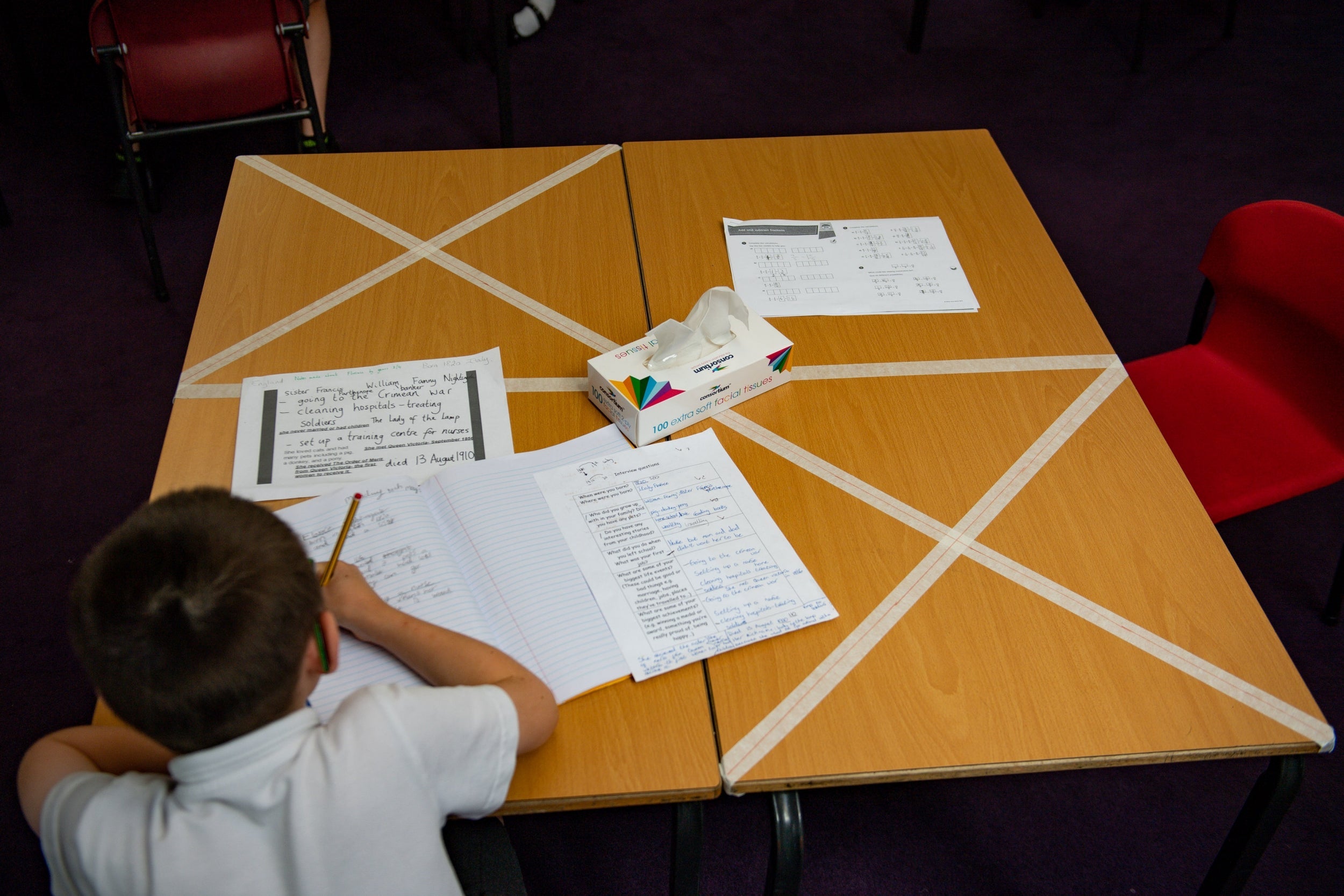 Social distancing measures as a child studies on a marked table at Kempsey Primary School in Worcester