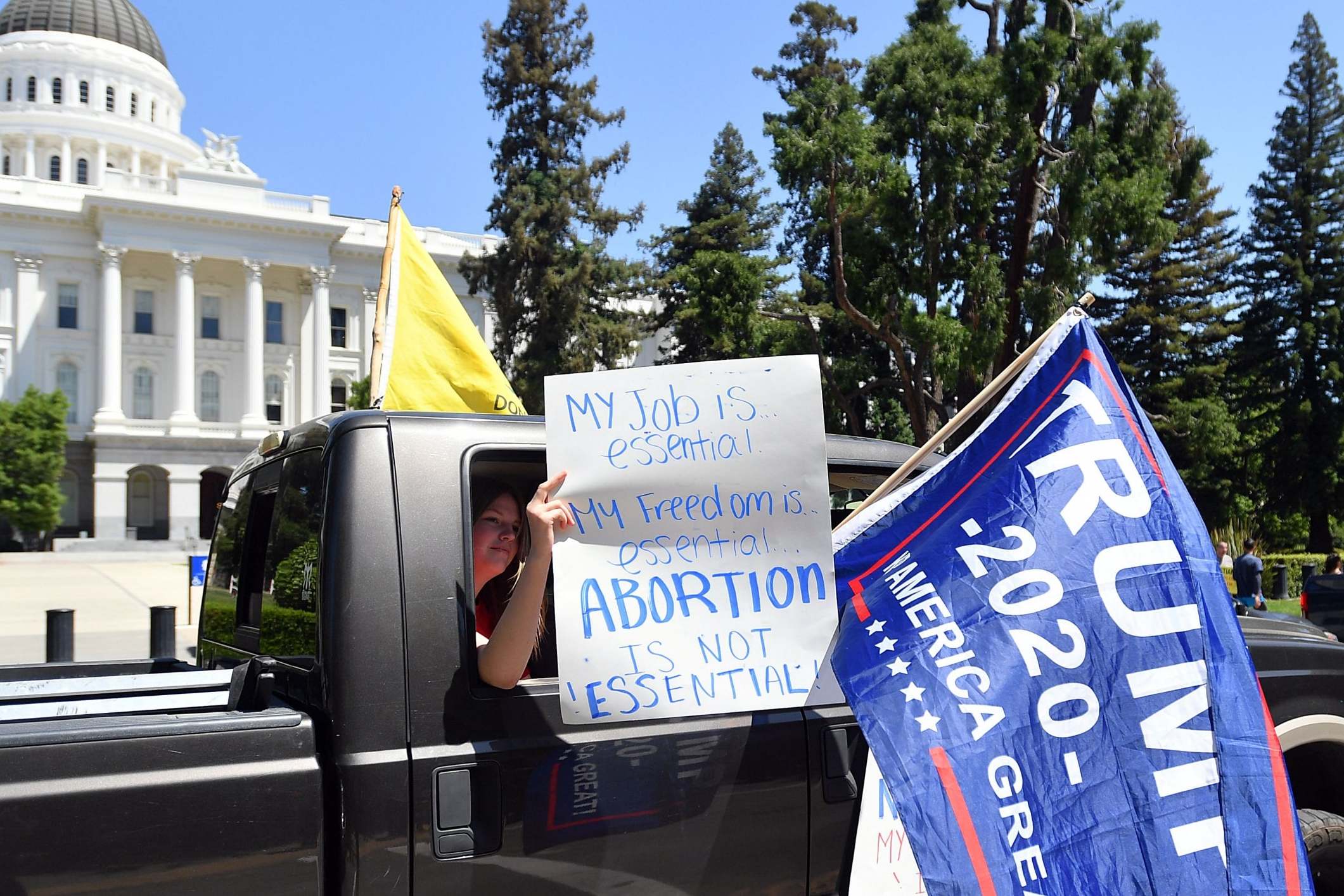 A woman holds an anti-abortion sign as hundreds of people gather in California to protest the lockdown