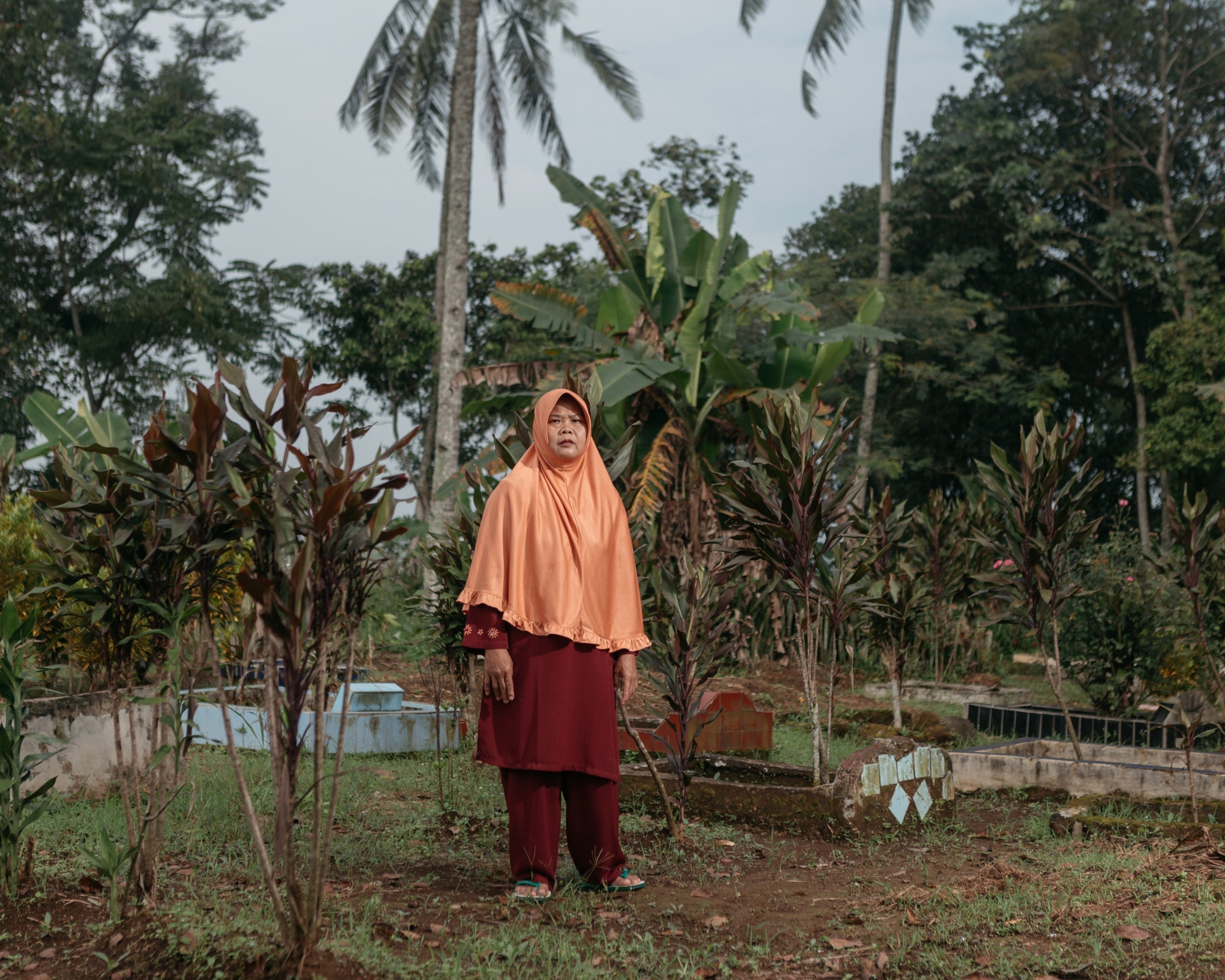 Iyum stands at Ciletuh Hilir’s cemetery, where the bodies of her two daughters were exhumed and reburied elsewhere (The Washington Post)