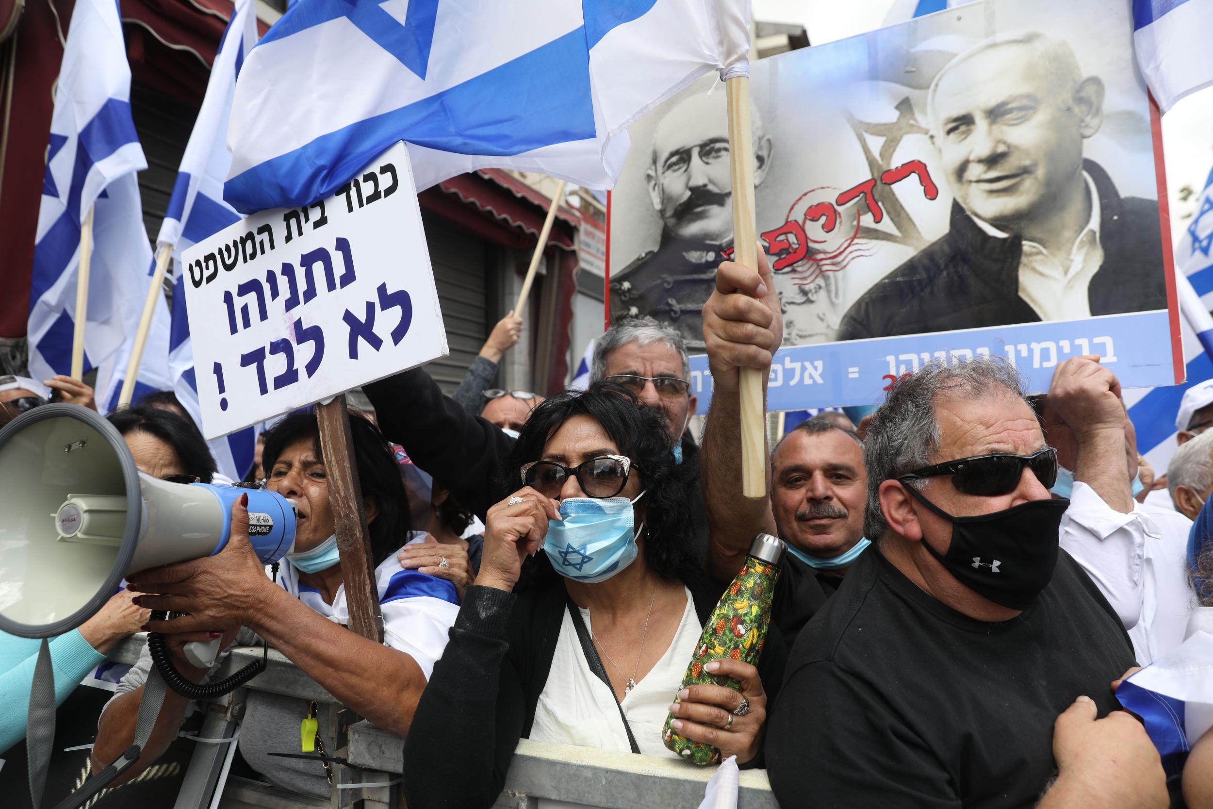 Israeli supporters hold flags and a poster depicting Netanyahu alongside French officer Alfred Dreyfus, who was unjustly convicted of treason in 1895 (Photo by Menahem Kahana/AFP via Getty Images)