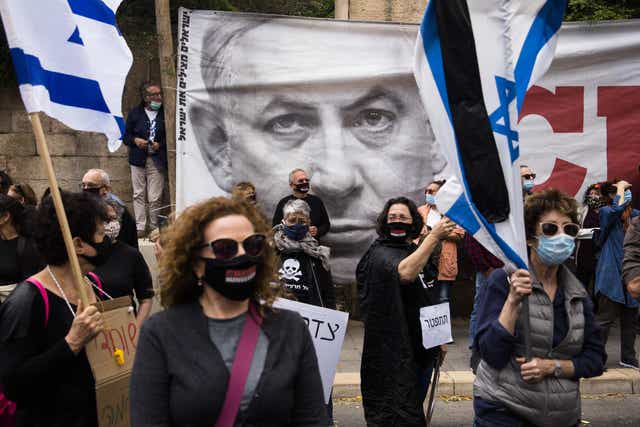 Israelis hold flags and signs as they protest against Israeli Prime Minister, Benjamin Netanyahu on May 24, 2020 in Jerusalem