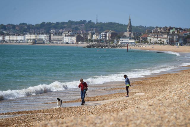 A man walks his dog on Preston beach in Weymouth on Sunday