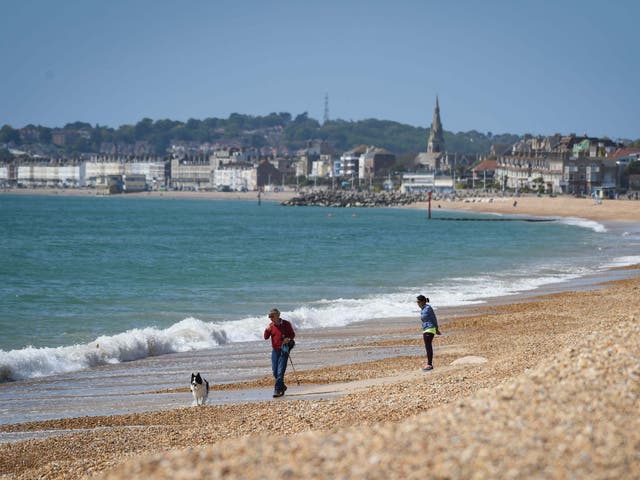 A man walks his dog on Preston beach in Weymouth on Sunday