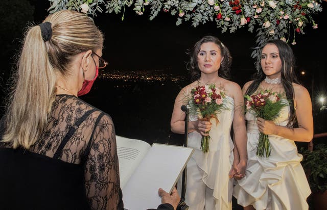 Newlyweds Alexandra Quiros (centre) and Dunia Araya (right) stand before a lawyer during their wedding in Heredia, Costa Rica on Tuesday