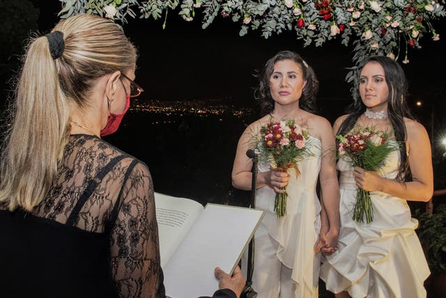 Newlyweds Alexandra Quiros (centre) and Dunia Araya (right) stand before a lawyer during their wedding in Heredia, Costa Rica on Tuesday