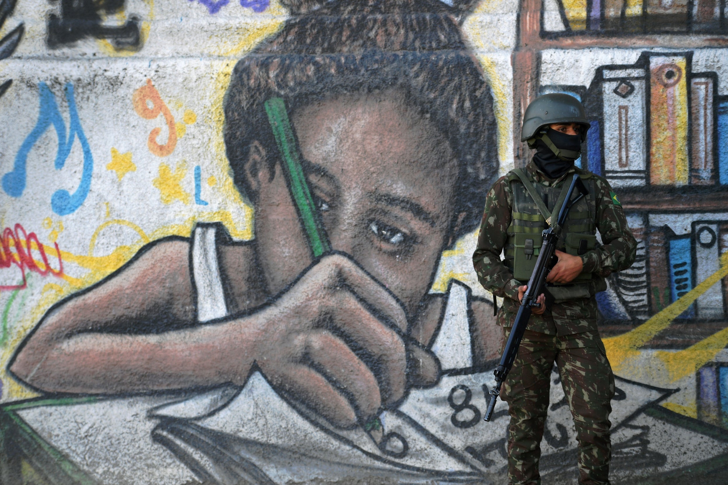 A soldier stands guard in front of a mural in Complexo de Alemao (AFP/Getty)