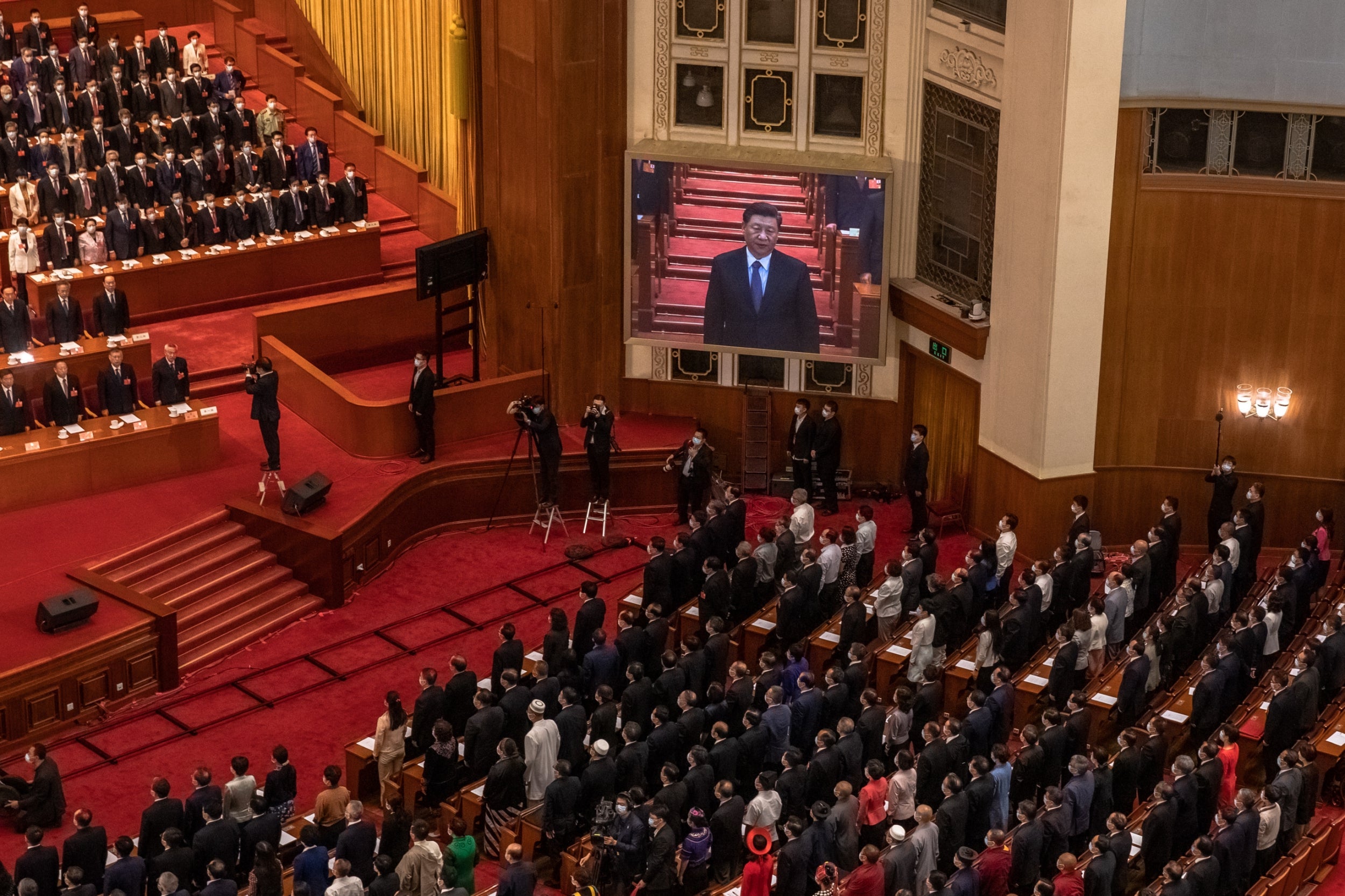 Delegates stand in front of a screen depicting Chinese president Xi Jinping during the closing session of the Chinese parliament at the Great Hall of the People, in Beijing, on Thursday