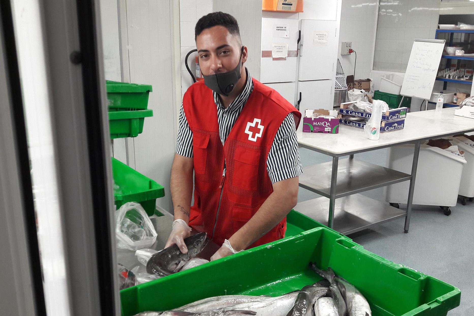 Alberto El Mansouri, a Red Cross volunteer who is also a recipient of basic necessities from the charity, packing fresh fish for needy families